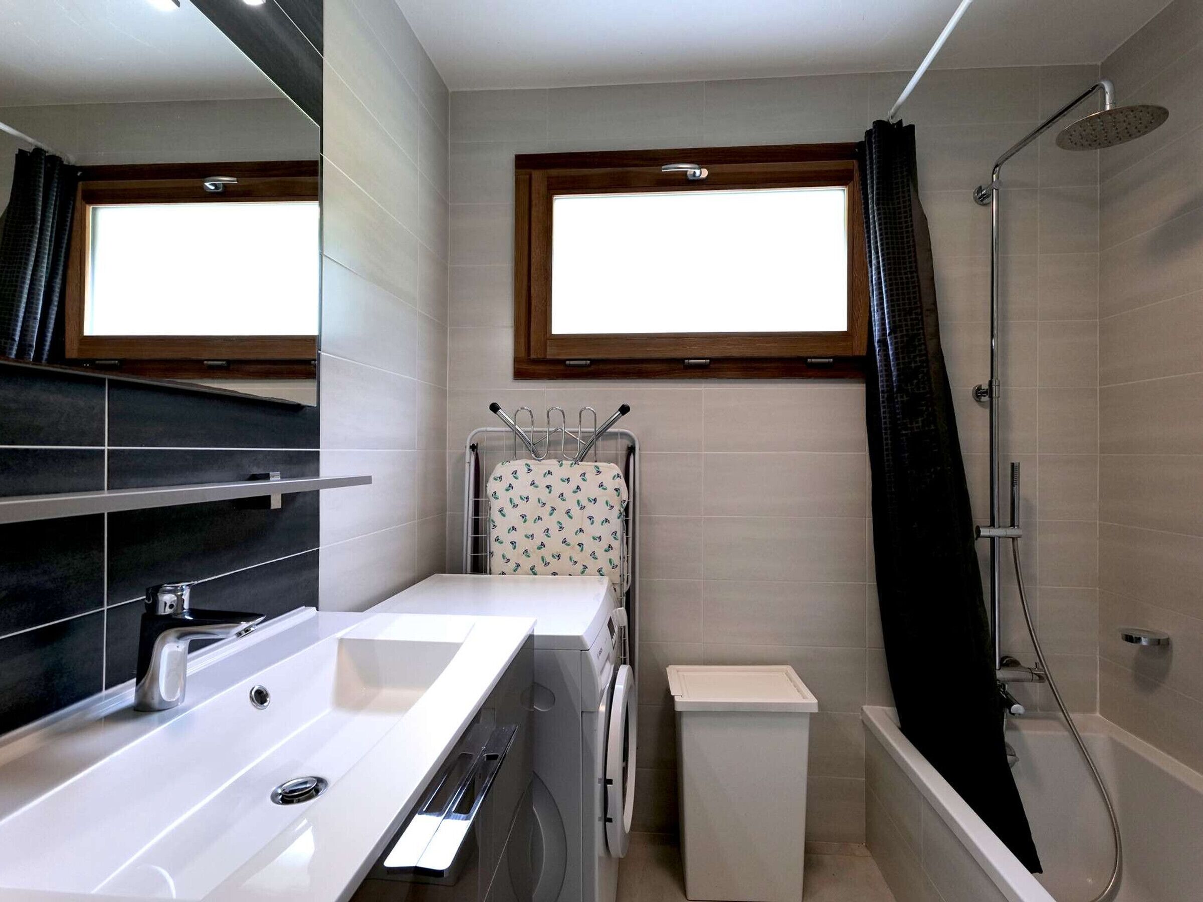 Une salle de bain moderne avec un lavabo blanc, une douche et une fenêtre située au-dessus du miroir.