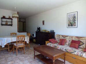 Ein gemütliches Wohnzimmer mit einer Holzdirektiva, einem Couchtisch und einem Esstisch mit Stühlen.