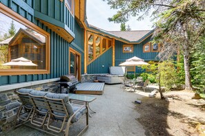 Une maison dotĂ©e dâun patio amĂ©nagĂ© avec des meubles dâextĂ©rieur, un barbecue et un mur en pierre.