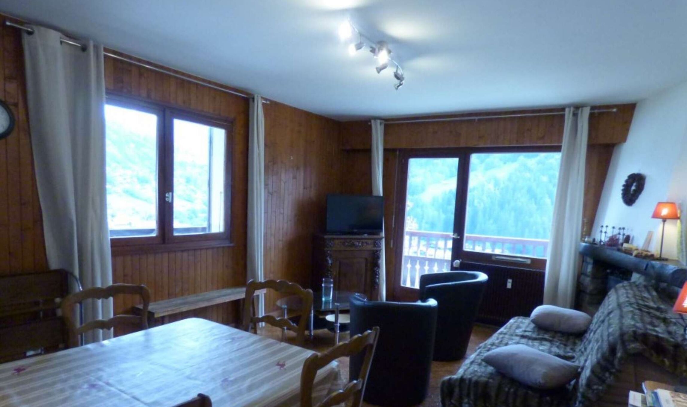 A cozy living room with a wooden interior, a dining table, and a sofa.