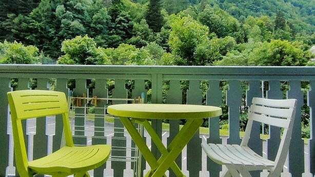 A balcony with two chairs and a table, overlooking a lush green forest and a mountain. - 3-Bedroom Apartment with Parking and Ski Locker, Cauterets (Cauterets)