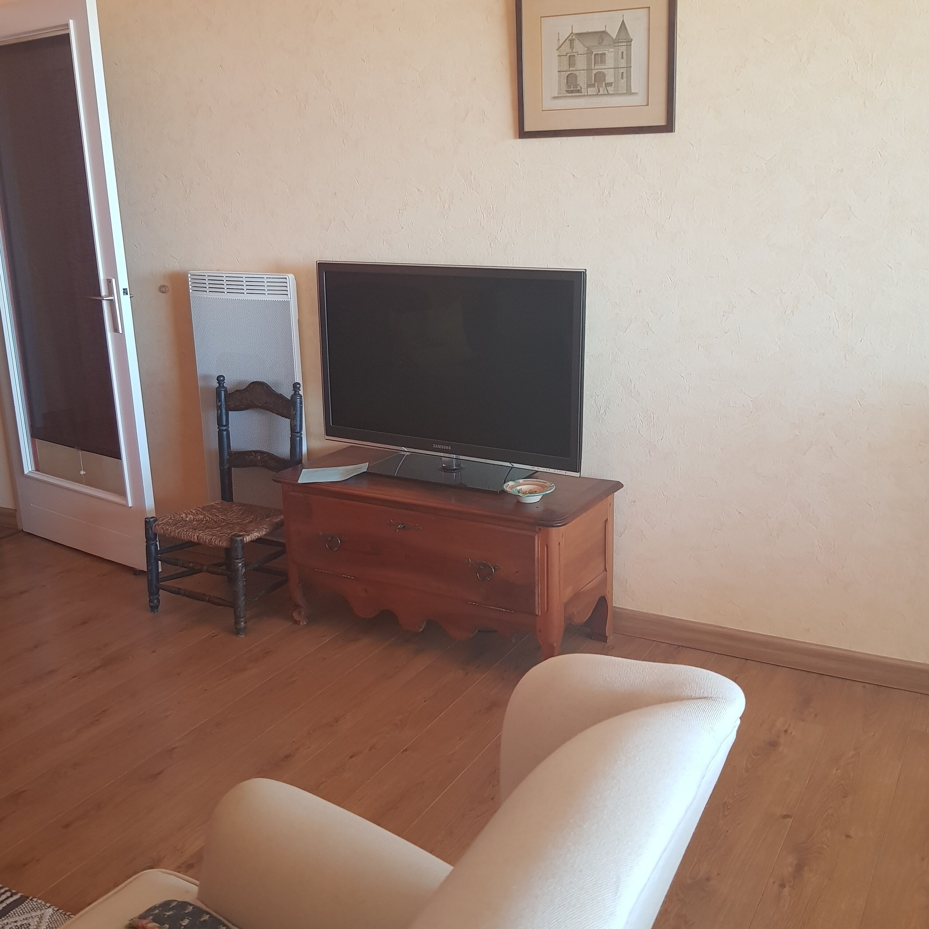 Una sala de estar con una televisión sobre un mueble de madera, una silla de mimbre y un sofá.