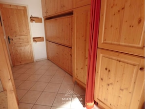 A room with wooden cabinets, a tiled floor, and a red curtain.