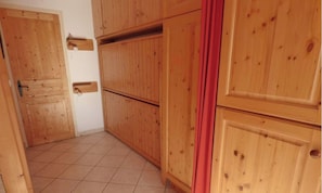 A room with wooden cabinets, a tiled floor, and a red curtain.