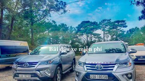 Dos SUVs estacionados en un estacionamiento con árboles al fondo.