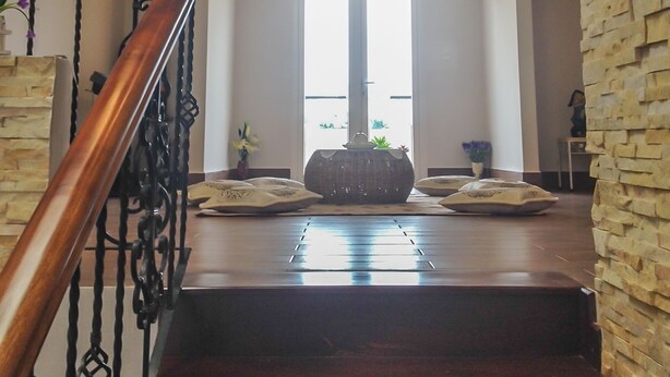 Una escalera con barandal de madera que lleva a un rellano con un gran ventanal.