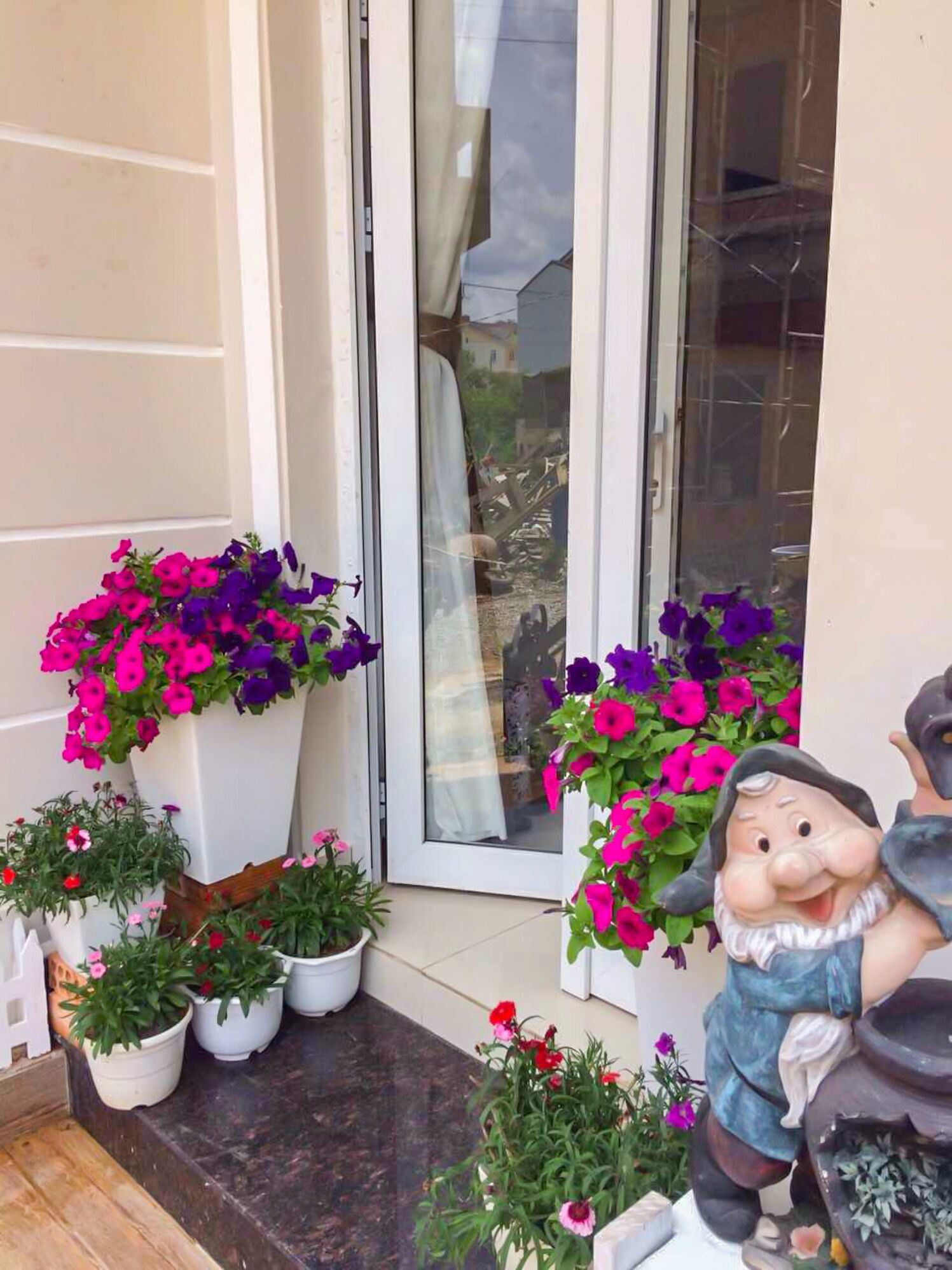 A front porch with potted plants and a decorative statue.