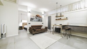 Una sala de estar moderna con sofá, una mesa de centro y una zona de cocina con mostrador y taburetes.