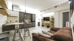 Una cocina moderna con armarios oscuros, una isla central y taburetes de bar.