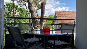 Un balcón con una mesa redonda y cuatro sillas, con vistas a un área residencial con árboles y casas.