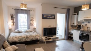 Un dormitorio moderno con cama, televisión y kitchenette.