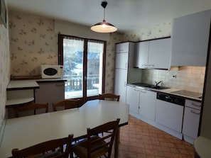 A compact kitchen with a dining table, chairs, a microwave, a refrigerator, and a sink.