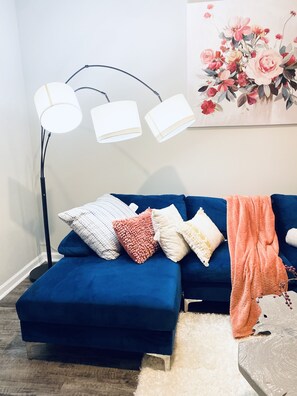 Relax in this inviting living room with a blue sofa, floor lamp, and beautiful floral artwork.