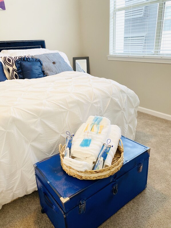 Cozy retreat with a large bed, featuring a white quilted duvet and pillows, and a convenient storage area for essentials.