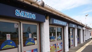 A row of storefronts with signage for 'Sands Amusements' and 'Win Tickets Here'.