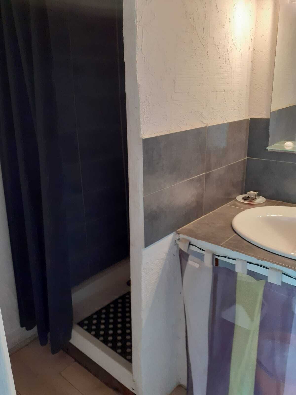 Un baño con ducha, lavamanos y toallero.