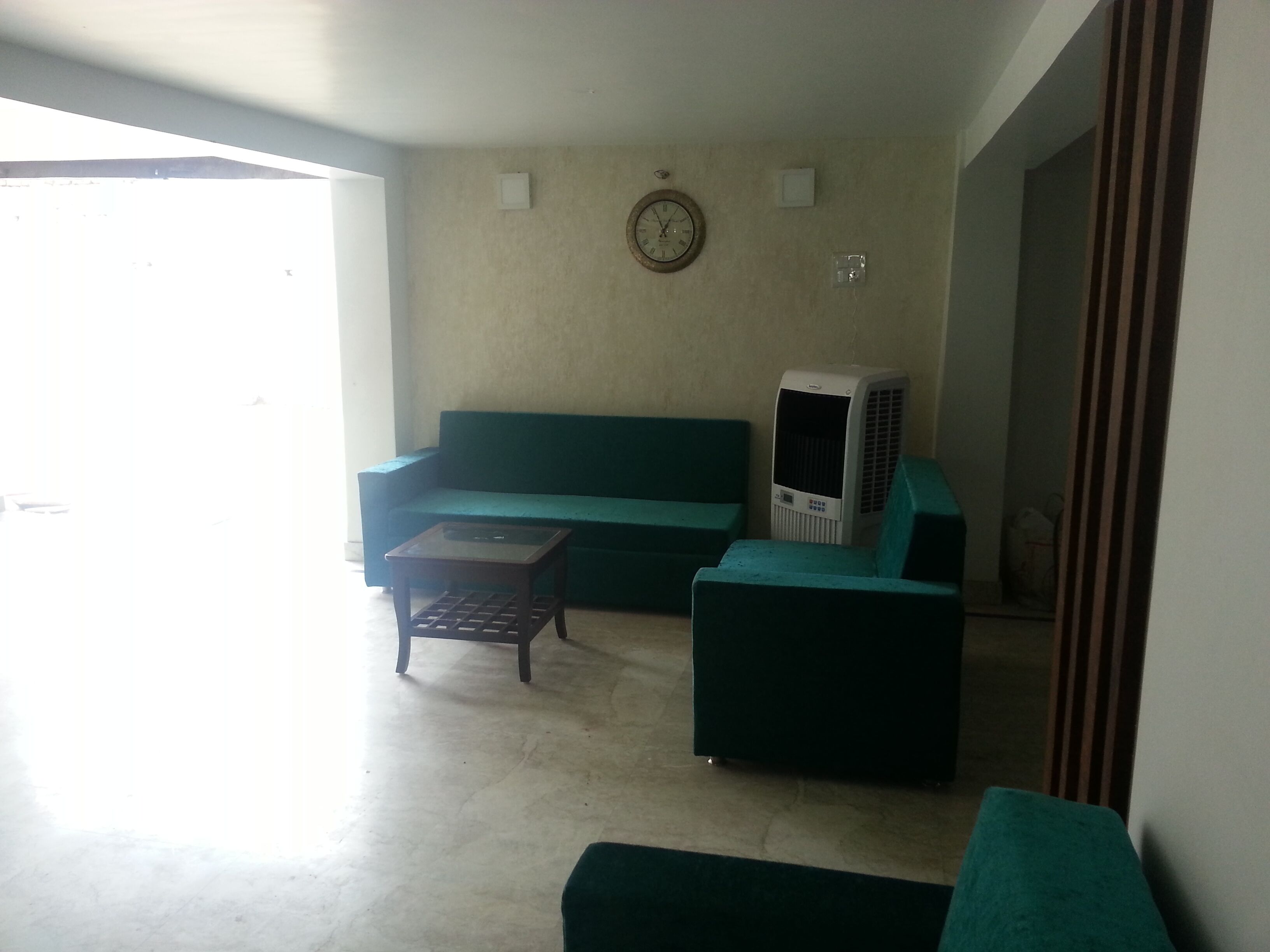 Una sala de estar con un sofá verde, una mesita de madera y un calefactor.