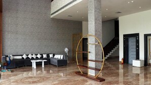 A modern lobby with a black sofa, white coffee table, and a unique gold and wood decorative piece. - Hotel Regal (Jabalpur)