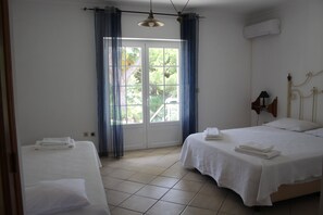 Ett hotellrum med två sängar, ett stort fönster med gardiner, en takfläkt och en luftkonditioneringsanläggning.