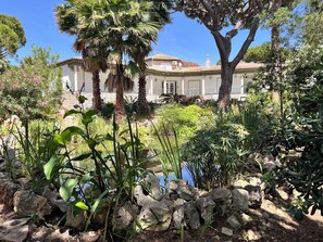 A house with a garden, a pond, and a stone wall.