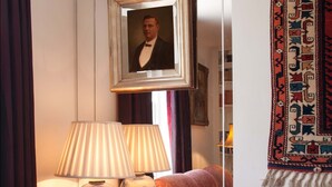 Un salon avec un canapé, une lampe, un tableau encadré et un tapis à motifs.