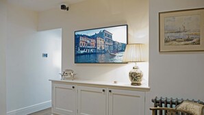 Une pièce comprenant une console blanche, un tableau encadré et un téléviseur diffusant une vue sur une ville.