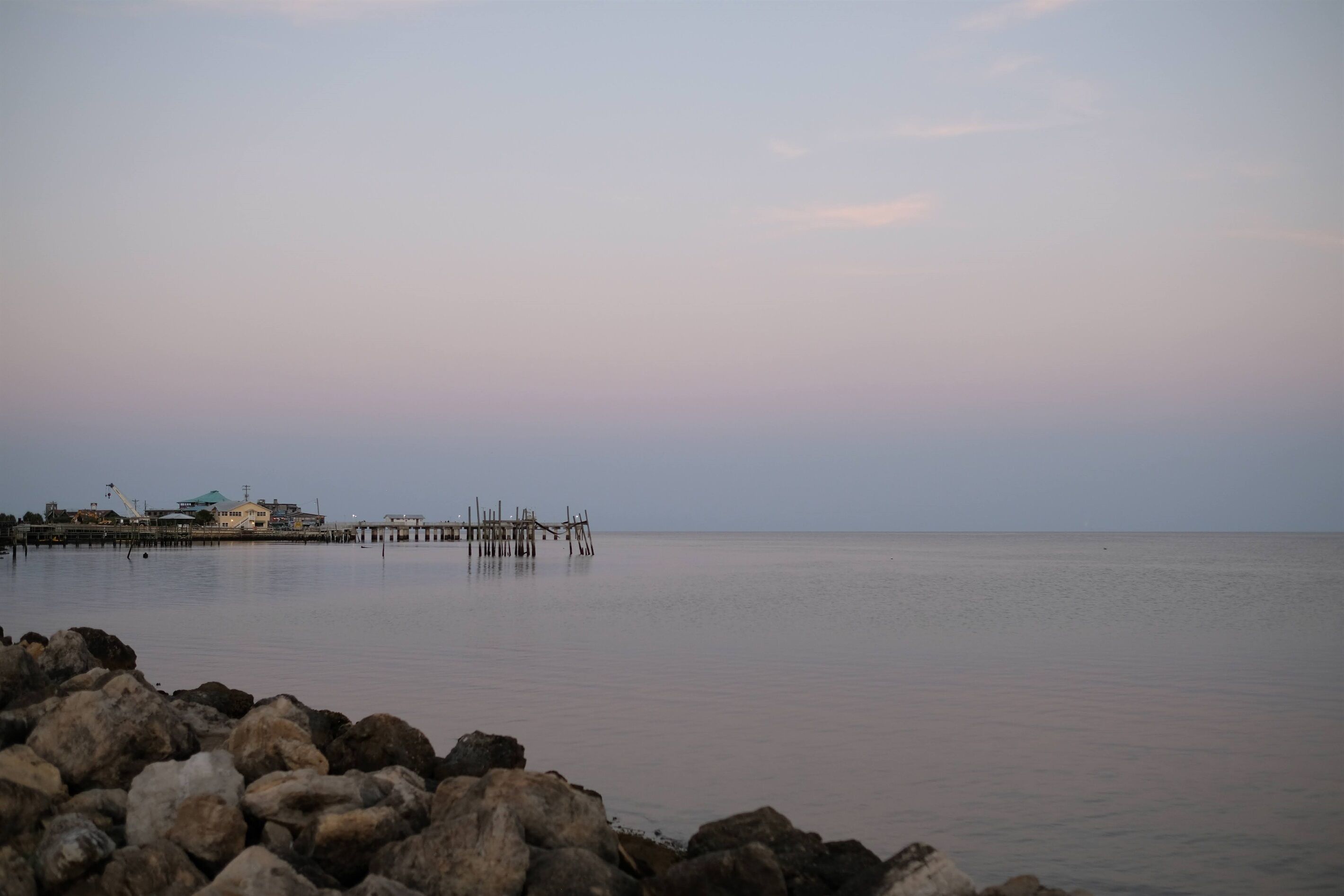 A calm waterfront with a pier extending into the water, surrounded by rocks.
