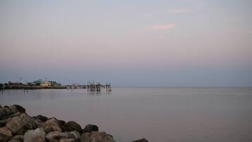 A calm waterfront with a pier extending into the water, surrounded by rocks.