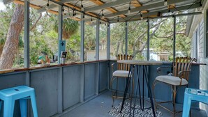A covered outdoor seating area with a table and chairs, surrounded by metal beams and string lights. - Hawthorne - Fisherman's Delight! Plenty of Parking (Cedar Key)