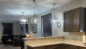 A modern kitchen with dark wood cabinets, a large island, and pendant lighting. - Modern condominium in Ennis (Ennis)