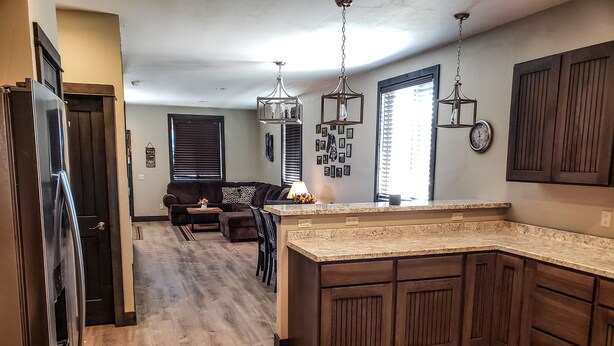 A modern kitchen with wooden cabinets, a granite countertop, and pendant lighting. - Modern condominium in Ennis (Ennis)
