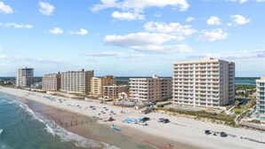 Ein Küstenhotelbereich mit mehreren Hochhäusern, einem Sandstrand und freiem Blick auf den Ozean.