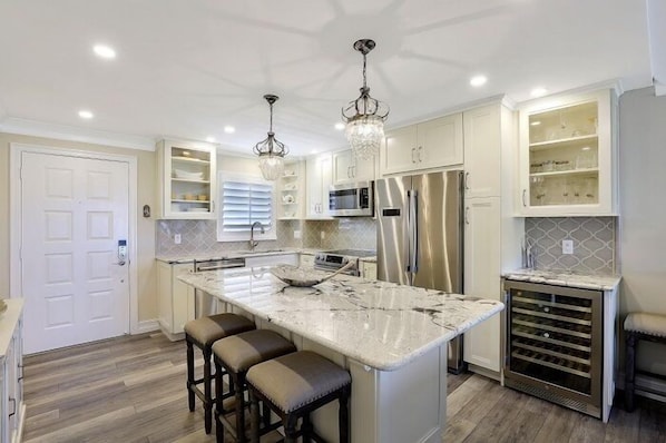 A modern kitchen with a large island, stainless steel appliances, and pendant lighting.