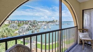 Ein Balkon mit Blick auf einen Yachthafen, Palmen und ein Gebäude im Hintergrund.