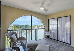 A balcony with wicker furniture, a ceiling fan, and a view of a marina.