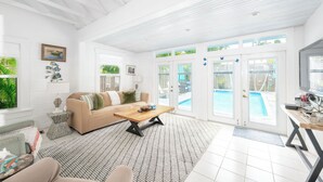 Un salon spacieux avec un canapé beige, une table basse en bois et un tapis à motifs.