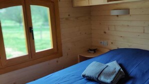En stuga med träpanel, ett rum med en säng, ett fönster och ett litet bord.