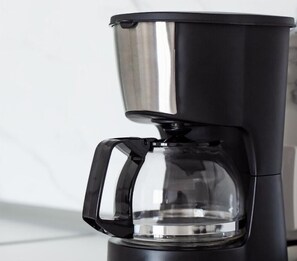 Een zwarte koffiezetapparaat met een transparant waterreservoir en een zwart handvat.