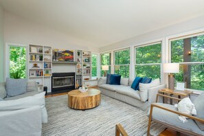 A spacious living room with a fireplace, large windows, and a cozy seating area.