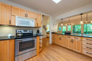 A modern kitchen with wooden cabinets, a stainless steel oven, and a microwave.
