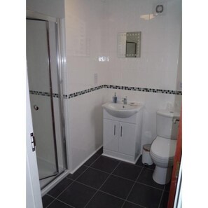 A bathroom with a glass shower door, a white sink with a mirror above it, and a toilet. - Newholme Cottage.........new for 2021 (Hunstanton)