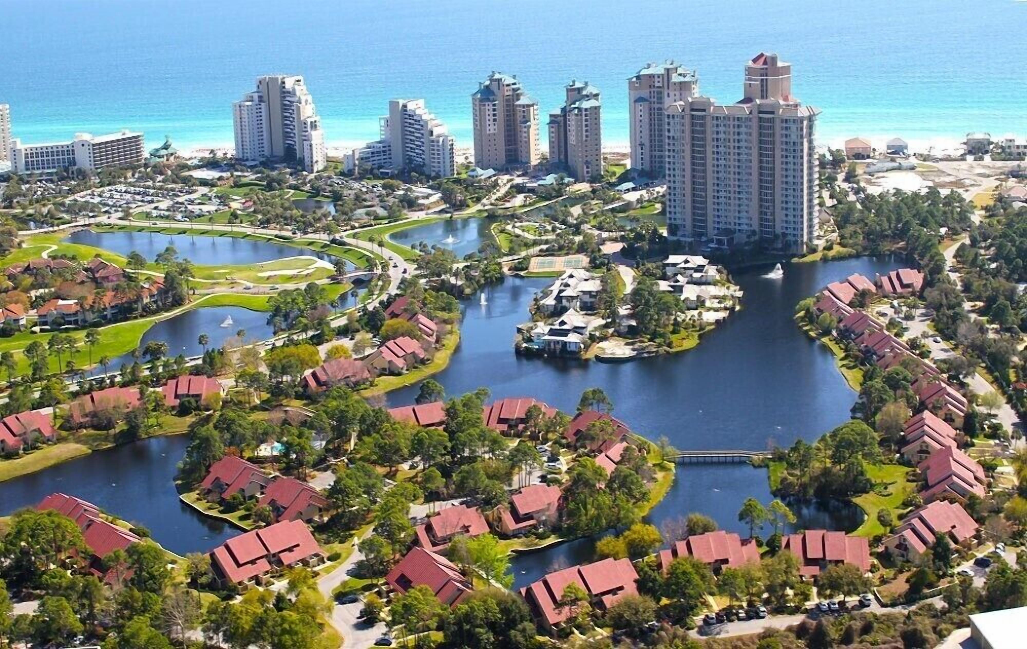 Een resort met meerdere gebouwen, een centraal gelegen waterpartij en veel groen eromheen.