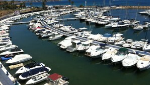 A marina with numerous boats docked in a circular layout, surrounded by a stone wall and palm trees. - Very nice apartment in 1st line of golf (VC)