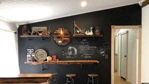 Uma área de bar moderna com prateleiras de madeira, um quadro-negro com comentários e decoração rústica.
