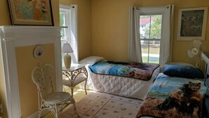 A room with two beds, a chair, a table, and a fireplace. - Pine Island Retreat - 3BR's, 1st & 2nd level porches NO LINENS PROVIDED (Chincoteague)