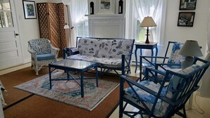 A living room with a sofa, chairs, a coffee table, a patterned rug, a fireplace, and artwork on the walls. - Pine Island Retreat - 3BR's, 1st & 2nd level porches NO LINENS PROVIDED (Chincoteague)