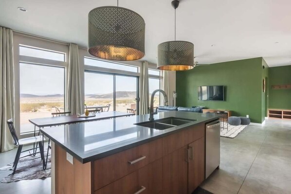 Una cocina moderna con una isla grande, un comedor con vistas y un espacio de sala con televisor.