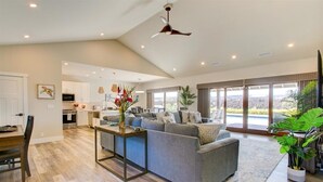 A spacious living area with a grey sofa, a dining table, and a kitchen in the background. - Luxury Home w/Pool + Spa | Sleeps 10 | Waikoloa Resort (Waikoloa)