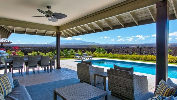 A covered outdoor area with a pool, seating, and a view of distant mountains. - Luxury Home w/Pool + Spa | Sleeps 10 | Waikoloa Resort (Waikoloa)