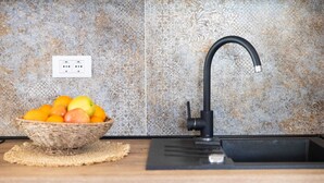 Una cocina con salpicadero de azulejos, un grifo negro y una cesta de fruta sobre la encimera.
